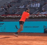 a man in a red shirt is running on a tennis court in front of a sign that says ' a ' on it