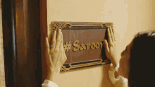 a woman holds up a sign that says #saroor on it