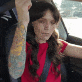 a woman with a tattoo on her arm is sitting in the driver 's seat of a car