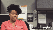 a woman in a pink shirt sits in front of a cubicle with a sign that says press access on it