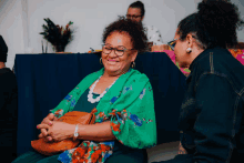 a woman in a green kimono sits next to another woman in a blue shirt