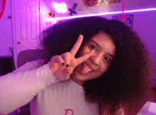 a girl with curly hair is giving the peace sign