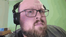 a man with glasses and a beard is wearing headphones .