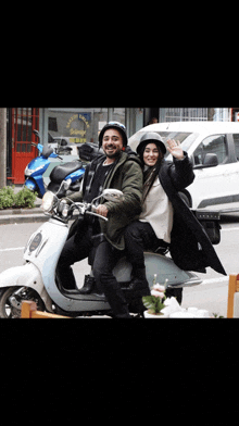 a man and a woman are riding a scooter on a city street