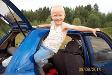 a child is sitting in the back of a blue car