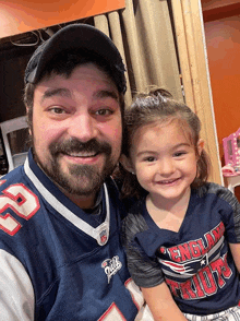 a man wearing a patriots jersey and a little girl wearing a patriots shirt