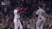 two baseball players high five each other in front of a crowd with the number 19 on the back of their jersey