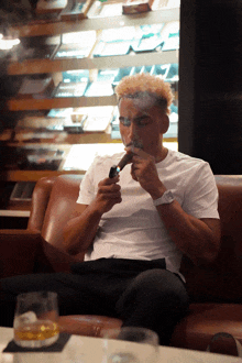 a man in a white shirt is smoking a cigar on a couch