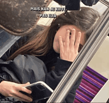 a woman covering her face with her hand while looking at her phone