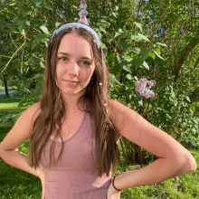 a woman wearing a headband with flowers on it stands in front of a bush with purple flowers