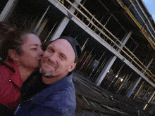 a woman kisses a man in front of a construction site