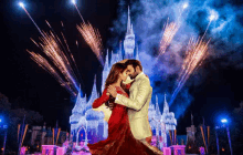 a man and a woman are dancing in front of a castle with fireworks behind them