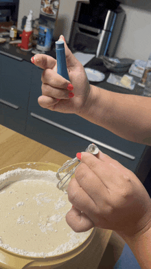 a woman with red nails is mixing a batter in a bowl with a whisk