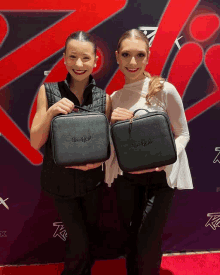 two women holding a black bag that says ' lucky girl ' on the front