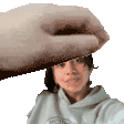 a woman is taking a selfie and a hand is holding her head .