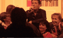 a man singing into a microphone in front of a group of women