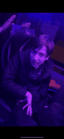 a young boy is sitting in a chair under a purple light .