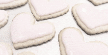 a bunch of heart shaped cookies with pink frosting on a table