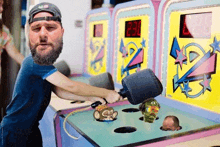 a man with a beard is playing a game of whack a mole with a hammer .