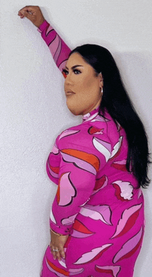 a woman in a pink dress is leaning against the wall