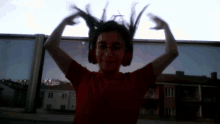 a girl wearing headphones and a red shirt has her hands in the air