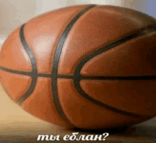 a basketball is sitting on a wooden table with the words " мы еблан " below it