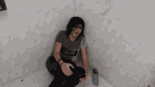 a person sitting in a bathroom with a bottle of shampoo nearby