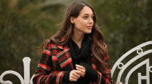 a woman in a plaid coat is standing on a bench