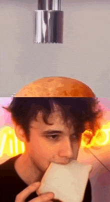 a young man is eating a piece of bread while a potato is falling from the ceiling .