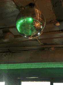 a green disco ball hangs from the ceiling of a building