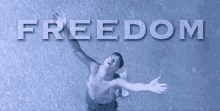 a man without a shirt is standing in the rain with his arms outstretched in front of the word freedom .