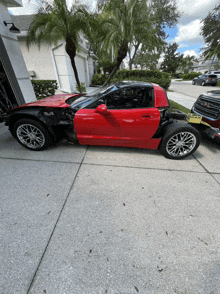 a red sports car with the door removed is parked in a driveway next to a gmc truck