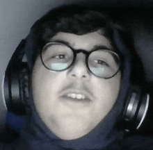 a man wearing glasses and headphones looks at the camera .