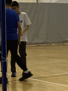 a man in a white shirt with a blue stripe on the sleeve is walking on a court