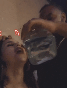 a man is pouring a glass of water into a woman 's mouth .