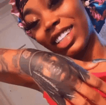 a woman is holding a tattoo of a man 's face on her forearm .