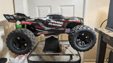 a black and red traxxas sledge rc truck sits on a table