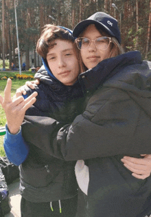 a girl wearing a calvin klein hat is hugging a boy wearing a black jacket