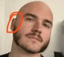 a close up of a man with a beard and a bald head with a red circle around his ear .