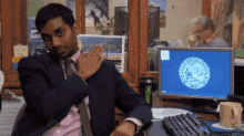 a man in a suit and tie is sitting at a desk in front of a computer screen that says new york state seal on it