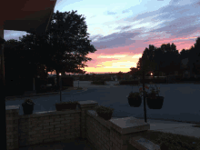 a sunset over a residential area with a brick wall and planters