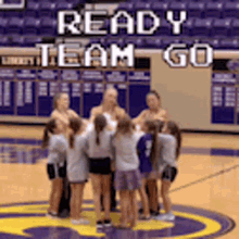 a group of girls are standing in a huddle on a basketball court with the words ready team go above them .