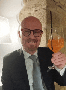 a man in a suit is holding a glass of orange liquid