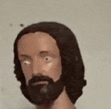 a statue of jesus with a beard and long hair is looking at the camera .