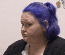 a woman with purple hair is making a funny face .