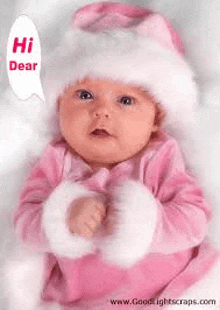 a baby wearing a pink santa hat and a pink outfit is talking to someone .