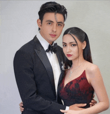 a man in a tuxedo and a woman in a red dress are posing for a picture