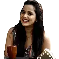 a woman sitting at a table with a cup of coffee smiling