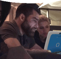 a man with a beard is looking at a laptop with the letter o on it