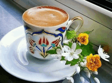 a cup of coffee sitting on a saucer next to flowers